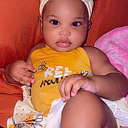 Zuri joined the competition — help win amazing prizes! baby, child, infant, yellow_clothing, headband, bee_pattern, couch, orange_background, pink_blanket, diaper, cute, portrait, indoors, relaxed, small_hands, big_eyes, soft_skin, sitting, looking_at_camera, clothing