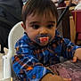 Zakaria participe au concours pour gagner de l'argent avec cette photo : toddler, child, pacifier, high_chair, plaid_shirt, table, restaurant, indoor, curious, baby, hand, face, clothing, furniture, person, food_service, drink_fridge, colorful, seated, portrait