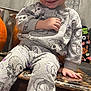 toddler, child, smile, pajamas, ghost_pattern, skeleton_pattern, blonde_hair, indoor, wooden_table, barefoot, curtain, pot, pumpkin, floor, hand, face, person, cute, cozy, home