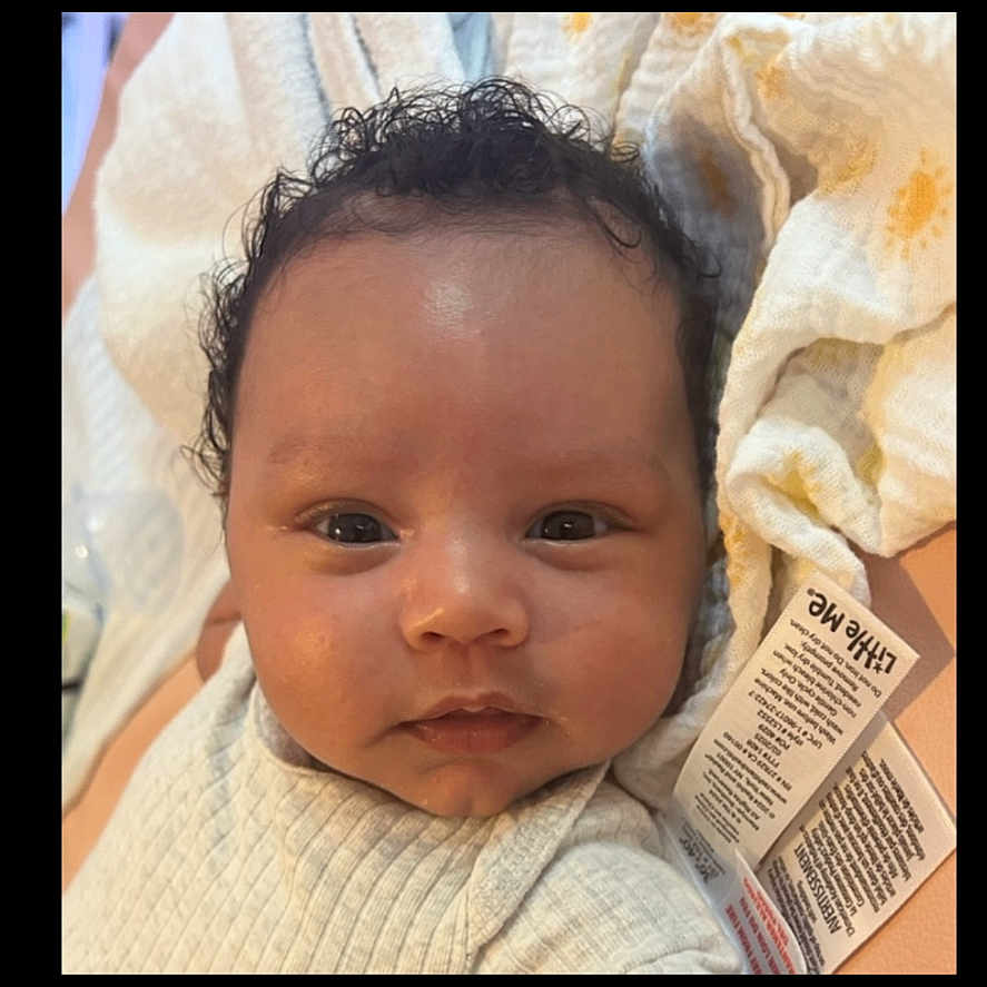 Lucas is registered to the contest to win money with this photo: baby, blanket, child, closeup, clothing, curly_hair, cute, expression, eyes, face, indoor, infant, mouth, newborn, nose, portrait, skin, soft, tag, texture