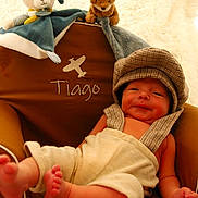Tiago participe au concours pour gagner de l'argent avec cette photo : baby, blanket, brown, child, clothing, cozy, cream, cute, hat, human, indoors, infant, plush_toy, portrait, relaxed, resting, seat, smiling, soft_texture, stuffed_animal