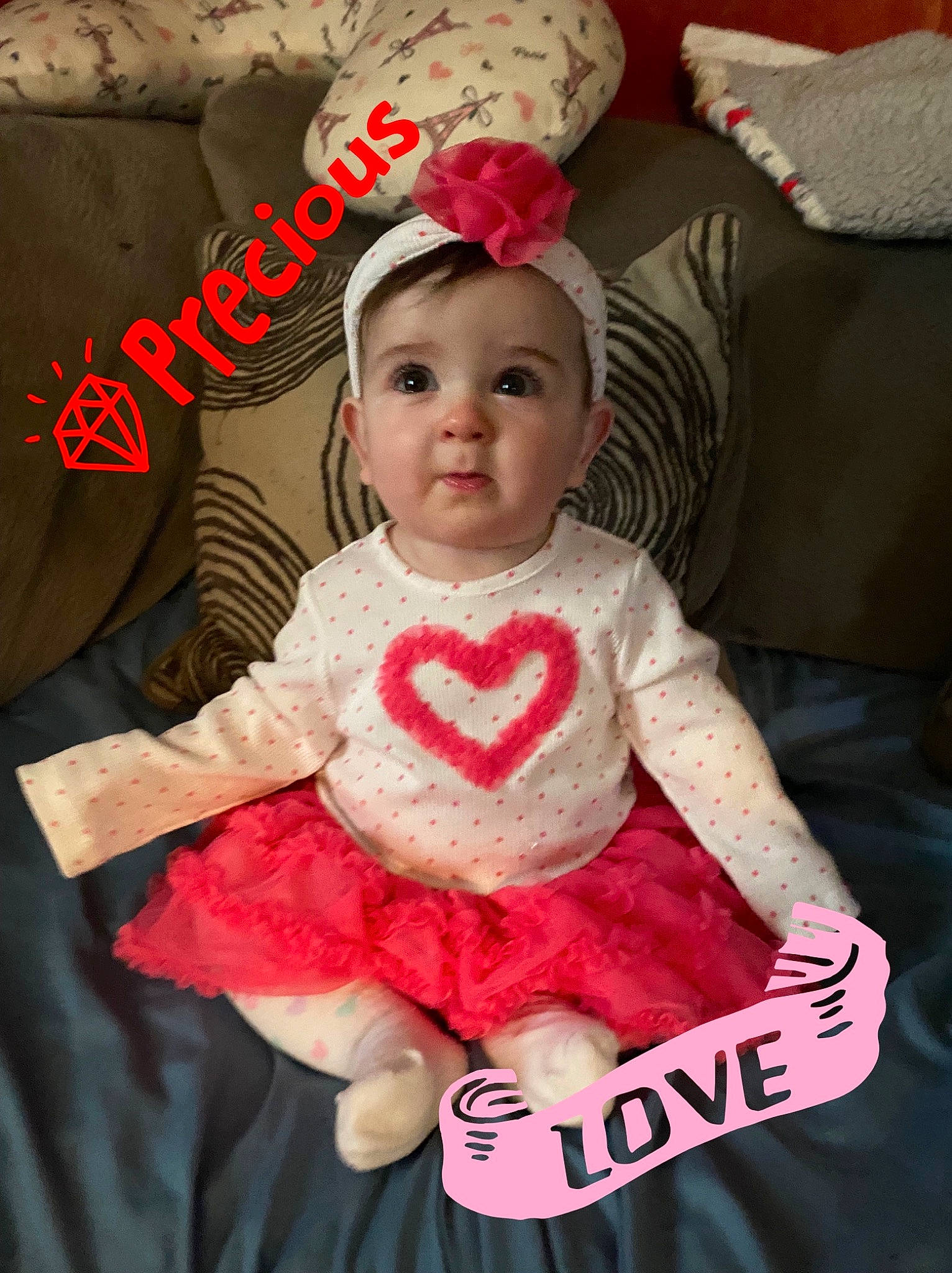 Justice is registered to the contest to win money with this photo: baby, baby_toddler_clothing, comfort, costume_hat, couch, event, font, happy, lap, linens, magenta, person, photo_caption, pillow, pink, product, red, room, sitting, sleeve