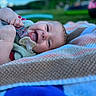 Ivy is registered to the contest to win money with this photo: baby, infant, child, portrait, smiling, pacifier, tongue, lying_down, blanket, colorful, outdoor, backyard, grass, sky, clouds, playground, summer, baby_clothing, close_up, happy