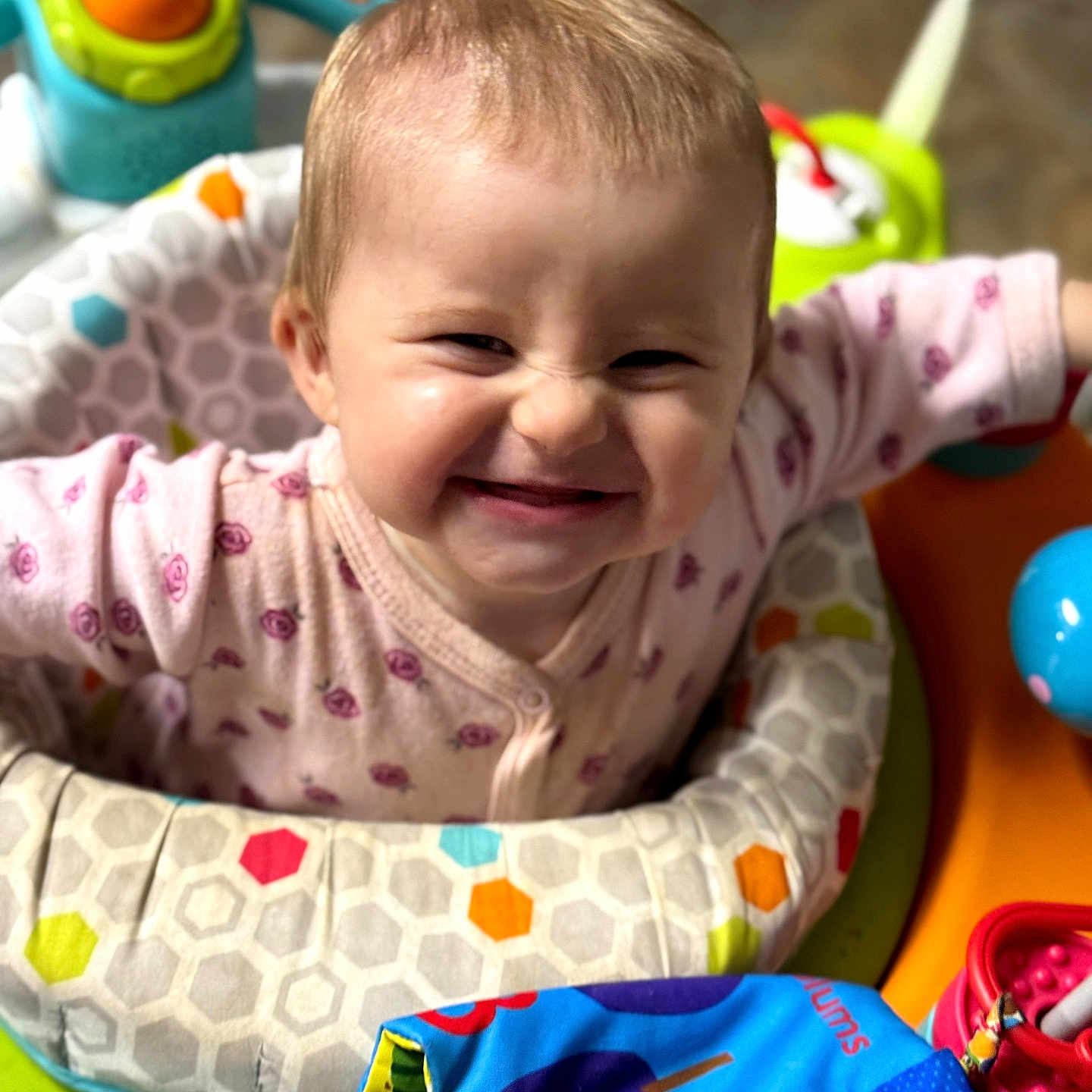Ivy is registered to the contest to win money with this photo: baby, infant, child, smiling, happy, portrait, face, sitting, playmat, activity_center, baby_toys, colorful, indoors, pink_clothing, onesie, playtime, nursery, close_up, grinning, toy