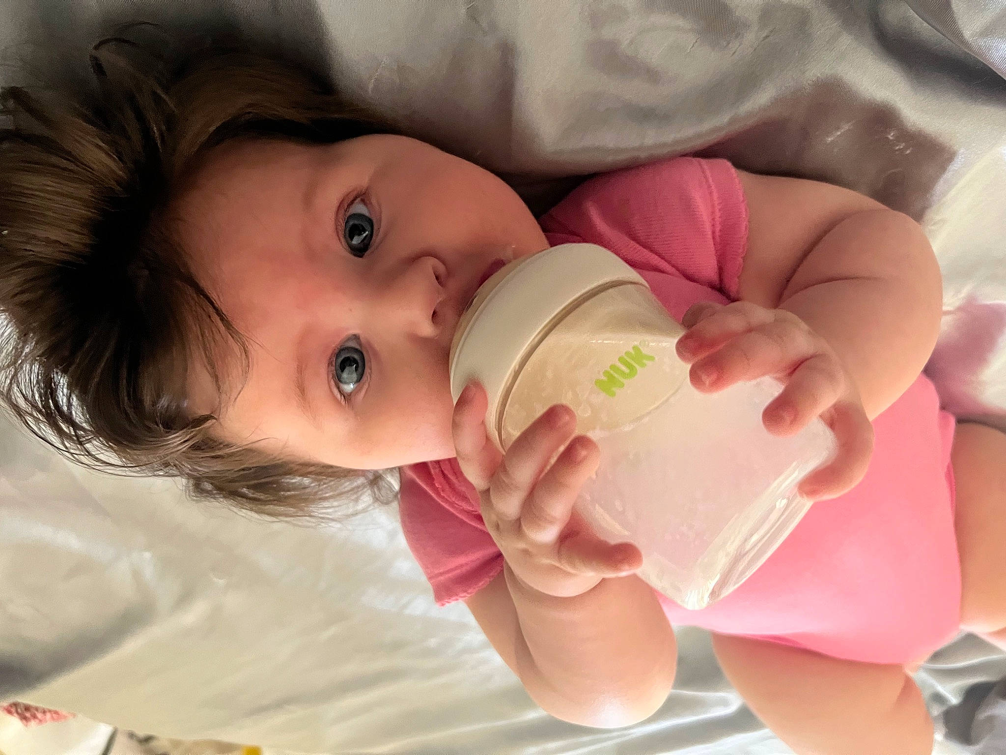 Isabel is registered to the contest to win money with this photo: baby, baby_bottle, baby_toddler_clothing, bottle, cheek, child, drinkware, eye, face, happy, head, infant_formula, lip, milk, mouth, nose, plastic_bottle, skin, toddler, water