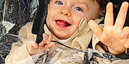 Lyssandro participe au concours pour gagner de l'argent avec cette photo : baby, beige_jacket, blue_eyes, child, closeup, cute, face, happy, outdoor, plastic, playful, portrait, rain_cover, raindrops, smiling, stroller, toddler, waving_hand, weather, wet