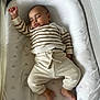 baby, sleeping, infant, striped_clothing, cozy, soft_bedding, peaceful, child, cute, relaxed, pajamas, white, cushion, indoors, young_child, resting, comfort, small_feet, raised_arm, portrait