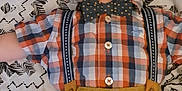Samuel is registered to the contest to win money with this photo: baby, child, infant, plaid_shirt, bow_tie, suspenders, patterned_blanket, lying_down, cute, portrait, young, fashion, clothing, face, expression, indoors, person, apparel, casual, adorable