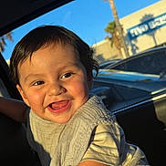 Ares joined the competition — help win amazing prizes! baby, child, smiling, tongue_out, portrait, car, car_interior, car_seat, sunlight, outdoor, palm_tree, parked_cars, storefront, blue_sky, happy, sitting, short_hair, striped_shirt, knit_vest, close_up
