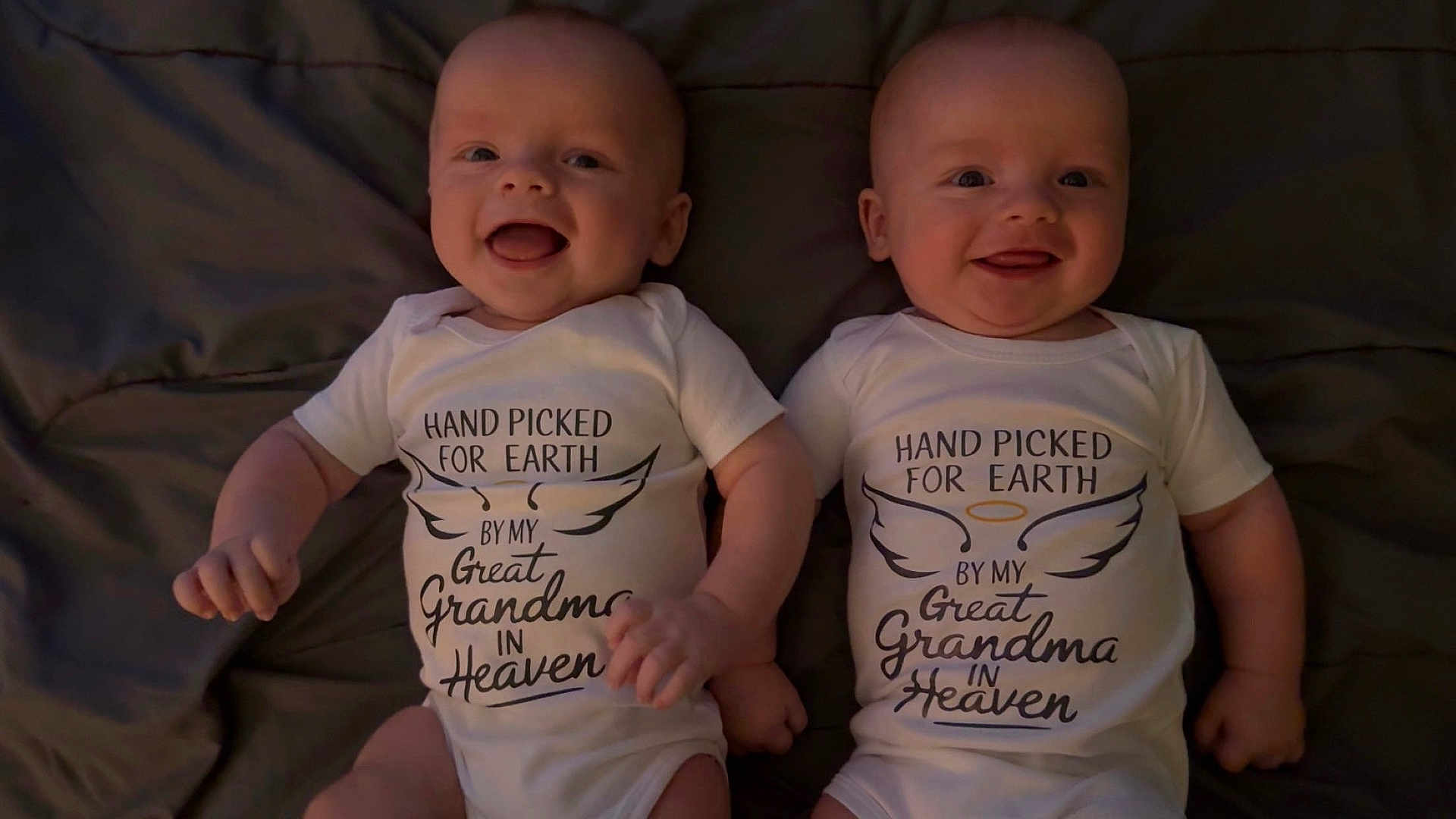 Titus-Pierce is registered to the contest to win money with this photo: baby, infant, smiling, onesie, matching_clothes, holding_hands, face, cute, happy, lying_down, blanket, indoors, portrait, two_babies, newborn, child, toddler, sweet, sibling, family
