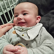 Hugo a rejoint le concours — aidez-le/la à gagner de superbes lots ! baby, infant, smiling, hands, clothing, bib, person, face, cozy, cute, indoor, crib, blanket, happy, child, closeup, young, skin, joy, expression