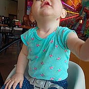 Miranda joined the competition — help win amazing prizes! baby, blue_eyes, child, clothing, colorful_background, curious, expression, face, hand, high_chair, indoor, neon_lights, person, polka_dot_pants, portrait, restaurant, seat_belt, sitting, toddler, turquoise_shirt