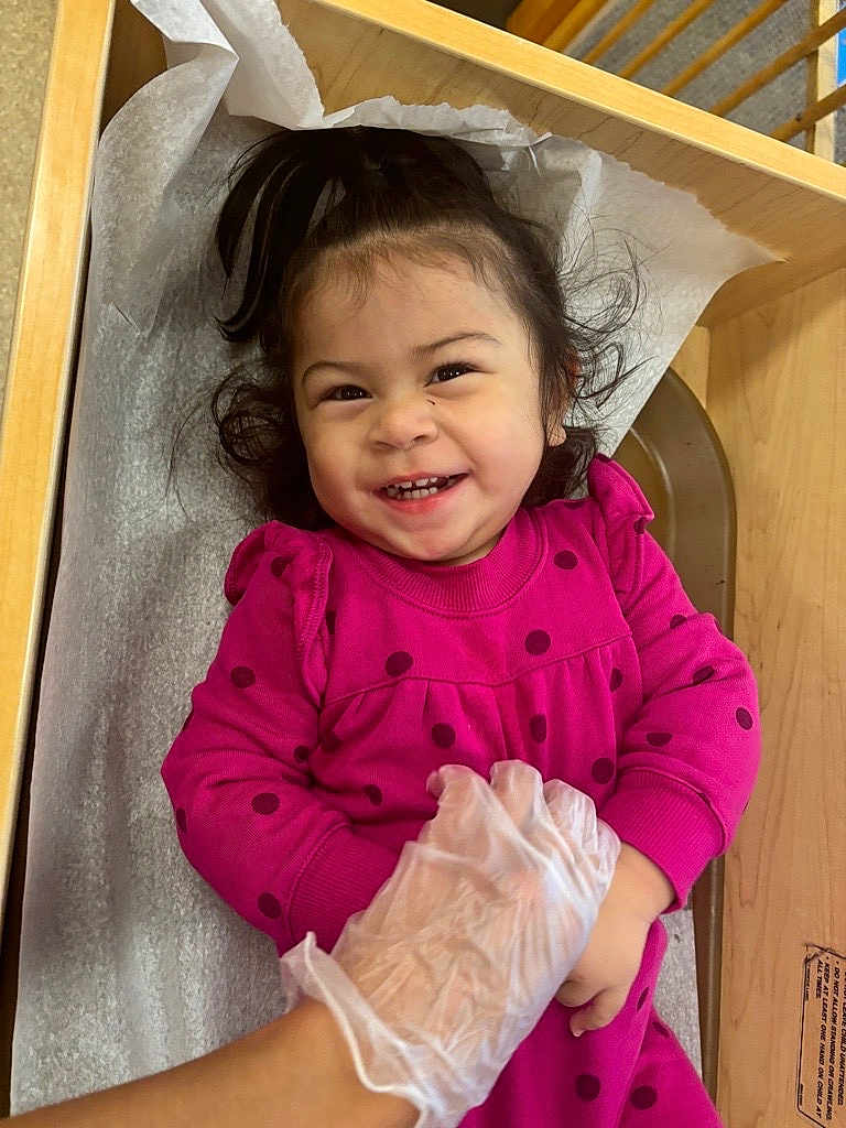 Raelynn joined the competition — help win amazing prizes! toddler, child, smiling, happy, polka_dot, dress, pink, gloves, hand, changing_table, hair, pony_tail, indoor, baby, person, cute, playful, skin, face, expression
