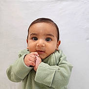 Aarav is registered to the contest to win money with this photo: baby, infant, child, face, hands, sweater, green_clothing, cute, portrait, closeup, expression, curious, chubby_cheeks, young, indoors, soft_background, skin, eyes, person, newborn