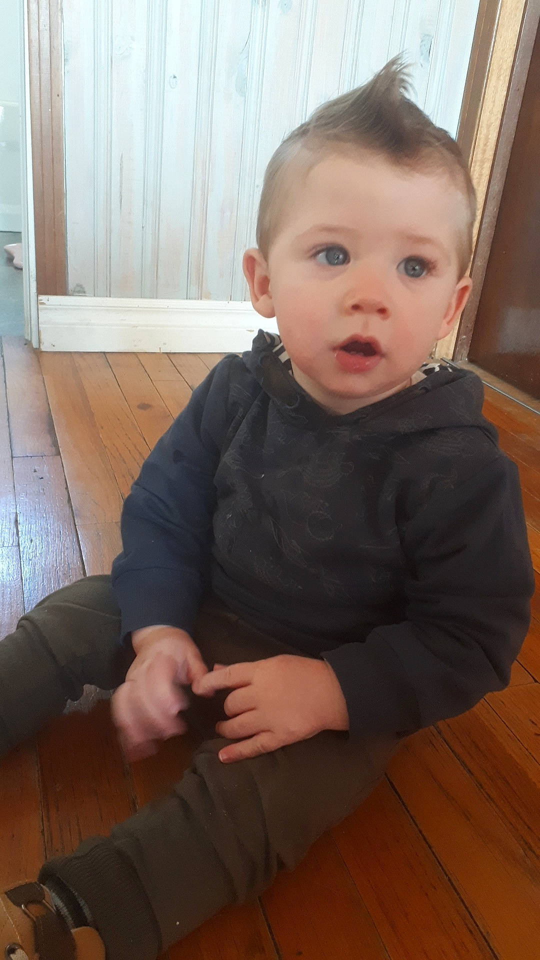 Calum is registered to the contest to win money with this photo: baby, cheek, child, chin, eye, face, floor, flooring, head, person, sitting, skin, standing, surprise, toddler, wood