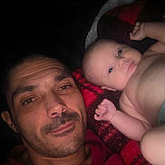 Evera is registered to the contest to win money with this photo: man, baby, face, portrait, blanket, skin, expression, closeup, lying_down, indoors, adult, child, human, together, candid, casual, warm, red, comfort, bond