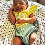 baby, newborn, smiling, sleeping, blanket, polka_dot, clothing, yellow_top, blue_shorts, cute, infant, happy, indoor, soft, cozy, peaceful, relaxed, skin, hand, face