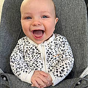 Kody is registered to the contest to win money with this photo: baby, child, smiling, happy, onesie, leopard_print, infant, seat, cushion, grey, hands, open_mouth, blue_eyes, cute, portrait, indoor, clothing, young_child, joyful, person