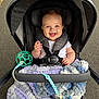 baby, stroller, blanket, smiling, child, outdoor, toy, happy, person, seatbelt, canopy, pavement, park, cute, infant, clothing, plaything, comfort, walking, daytime