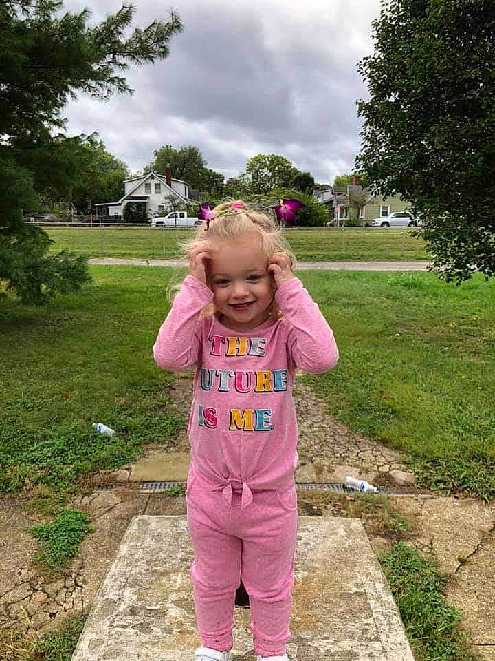 Addilynne is registered to the contest to win money with this photo: active_pants, baby_toddler_clothing, botany, cloud, face, grass, grassland, happy, joy, leaf, leisure, meadow, outerwear, people_in_nature, person, pink, plant, sky, smile, summer