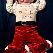 Stella joined the competition — help win amazing prizes! baby, black_belt, celebration, child, christmas_outfit, cute, dark_background, festive, holiday, holiday_clothing, infant, lying_down, newborn, pacifier, portrait, red_hat, ruffled_pants, smiling, velvet_pants, white_top