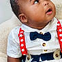 baby, child, infant, suspenders, bow_tie, stars, stripes, red, white, blue, clothing, cute, portrait, indoor, seated, curious, face, hand, furniture, soft