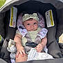baby, car_seat, headband, toy, blanket, infant, child, seatbelt, outdoor, grass, cute, smile, face, person, clothing, sitting, soft_toy, fabric, safety_harness, head