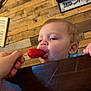 Ivan joined the competition — help win amazing prizes! toddler, child, popsicle, hand, wooden_wall, bow, sign, indoor, face, mouth, blue_clothing, high_chair, person, food, snack, cute, young_child, close_up, eating, summer