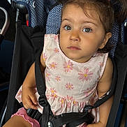 Delyar is registered to the contest to win money with this photo: toddler, child, stroller, pink_dress, pigtails, seatbelt, curious, expression, indoor, person, baby, clothing, seat, safety_harness, cute, portrait, young_child, small_hands, looking_up, casual