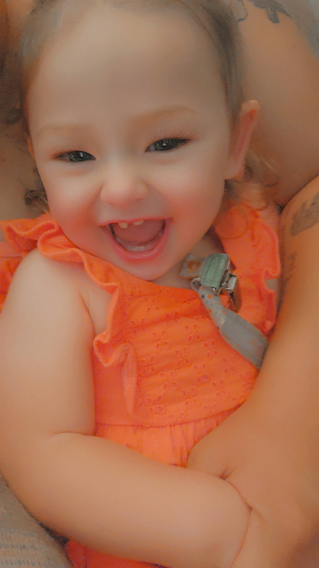 Darla is registered to the contest to win money with this photo: arm, baby, baby_toddler_clothing, cheek, child, comfort, finger, gesture, happy, human_body, iris, joy, lip, mouth, nose, orange, person, pink, skin, smile