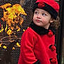 toddler, child, red_coat, hat, roses, fireplace, fire, mesh_screen, outdoor, winter_clothing, curious, portrait, warm, glowing, face, person, standing, looking_away, cute, seasonal
