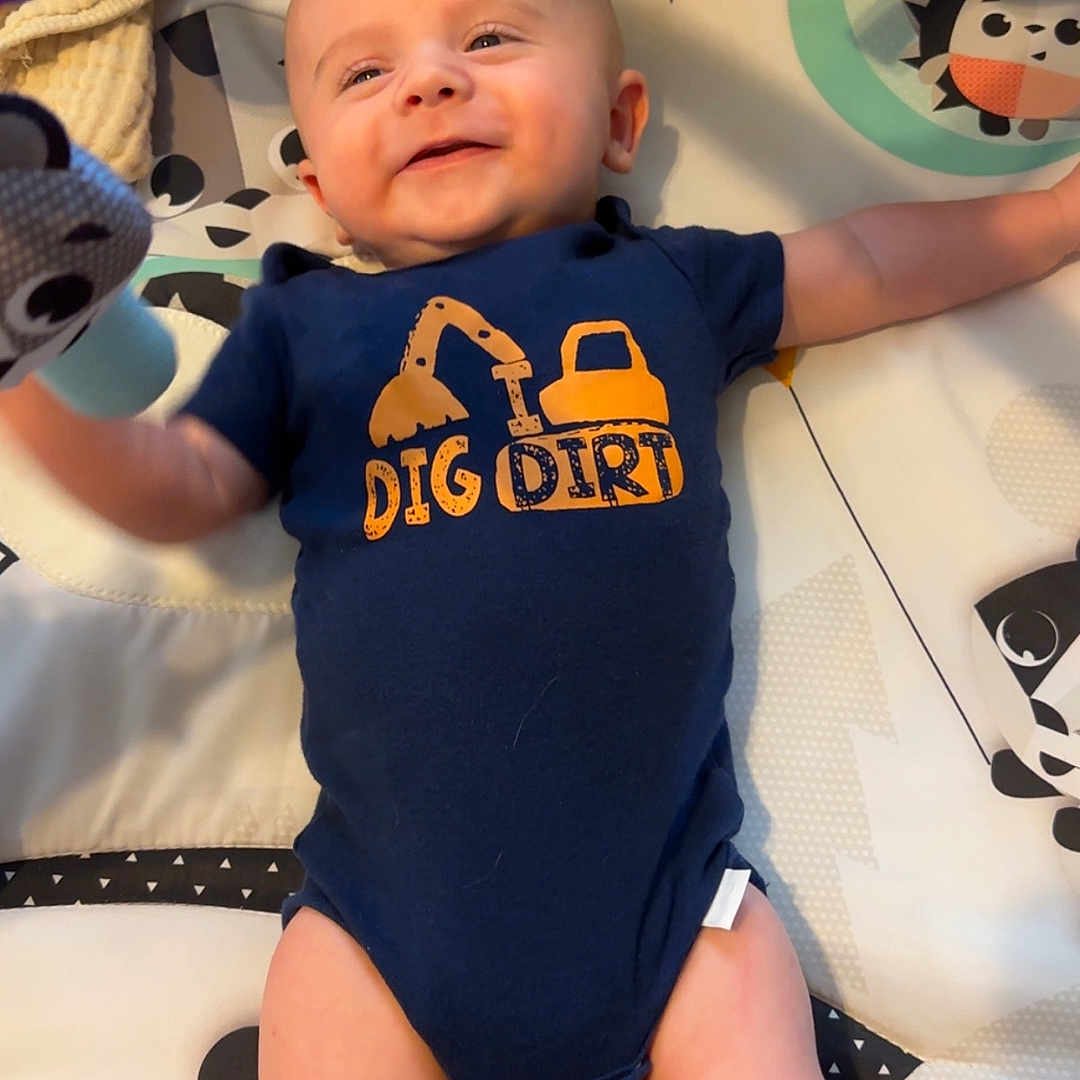 Dawson is registered to the contest to win money with this photo: applique, baby, bed, bodypart, clothing, crib, cushion, face, finger, furniture, hand, head, infantbed, newborn, pattern, person, photography, portrait, standing, t_shirt