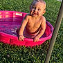 toddler, child, pool, water, smiling, outdoor, grass, sunlight, summer, happy, blue_eyes, play, splash, pink_pool, bare_chest, nature, daylight, cute, fun, young_child