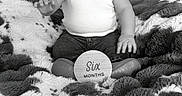 Ryland joined the competition — help win amazing prizes! baby, child, infant, six_months, cap, hat, white_shirt, jeans, smiling, happy, sitting, blanket, fluffy, patterned_blanket, wooden_sign, milestone, portrait, indoor, cute, young_child