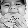 Ryland is registered to the contest to win money with this photo: baby, child, face, cap, hand, wooden_sign, milestone, teething, black_and_white, portrait, cute, infant, closeup, chewing, young_child, curious, smiling, person, clothing, indoors