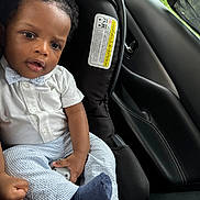 Noah is registered to the contest to win money with this photo: baby, child, car_seat, infant, clothing, white_shirt, bow_tie, striped_pants, blue_socks, curly_hair, face, hands, car_interior, window, seatbelt, safety, portrait, cute, young, indoors