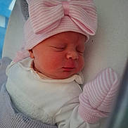 Alexis-Paige is registered to the contest to win money with this photo: newborn, baby, sleeping, pink_bow, mittens, blanket, white_clothing, closeup, face, peaceful, infant, soft_texture, plush_toy, headwear, cute, indoors, portrait, resting, child, cozy