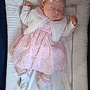 Alexis-Paige is registered to the contest to win money with this photo: baby, sleeping, infant, pink_dress, headband, flower, white_cardigan, socks, mattress, patterned_bedding, cute, peaceful, soft_texture, indoor, child, portrait, newborn, resting, cozy, hands_up