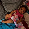 baby, blanket, child, colorful, couch, cushion, dark_lighting, home, indoor, infant, lying_down, pink_clothing, plush_toy, portrait, relaxed, sitting, sofa, stuffed_animal, teddy_bear, wide_eyed