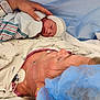 baby, bed, bed_sheet, blanket, face, hand, hat, healthcare, hospital, hospital_gown, infant, medical, medical_equipment, mother, newborn, nurse, patient, person, skin, surgical_cap
