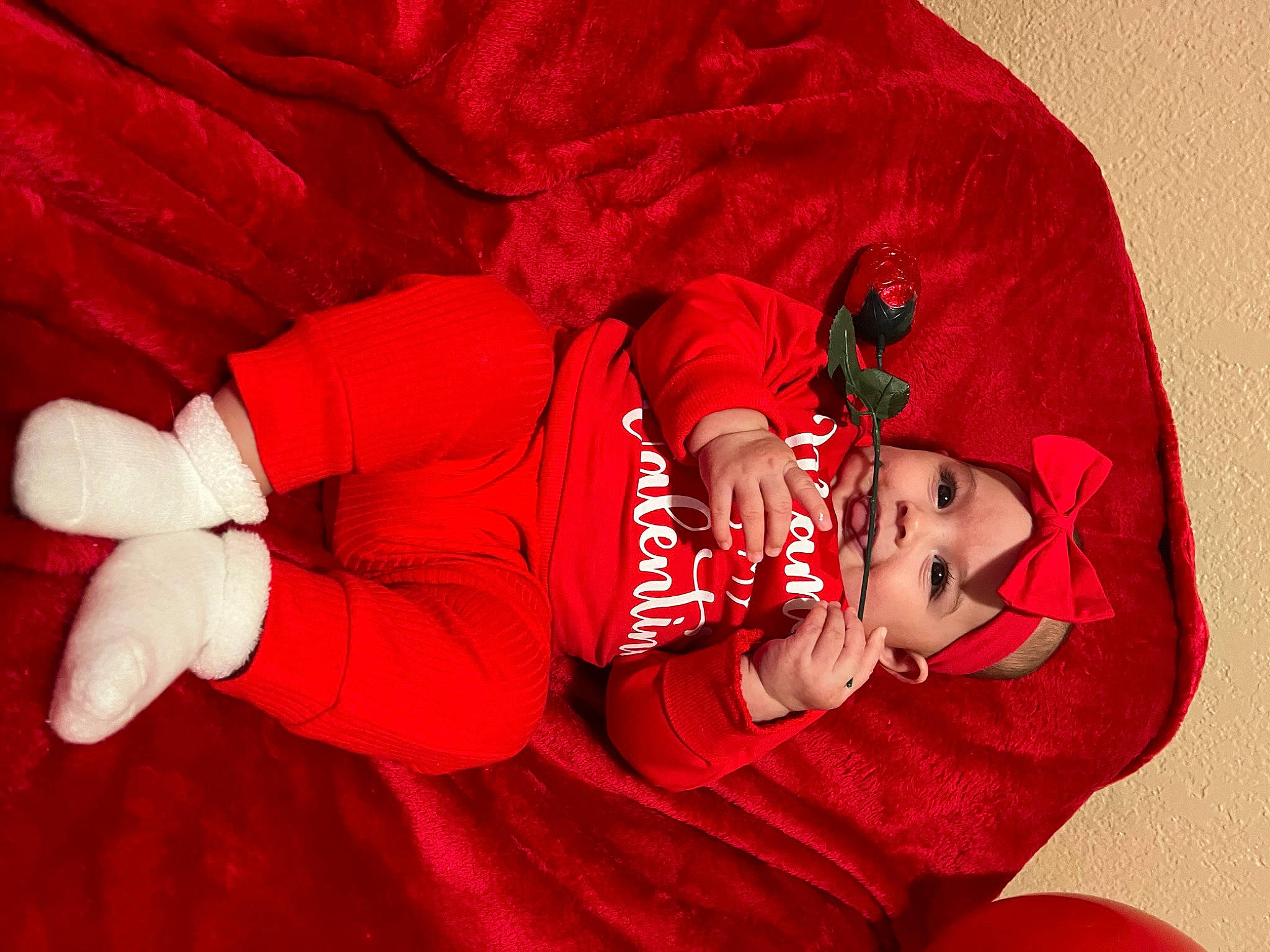 Valeria is registered to the contest to win money with this photo: baby, baby_toddler_clothing, carmine, child, comfort, event, eye, happy, headwear, human_body, human_leg, linens, magenta, person, pink, red, room, sitting, sleeve, textile