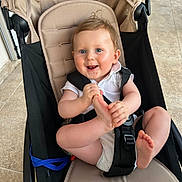 Charlie a rejoint le concours — aidez-le/la à gagner de superbes lots ! baby, child, stroller, seatbelt, foot, hands, smiling, happy, indoor, floor, tile, clothing, white_shirt, hair, face, blue_eyes, infant, cute, person, sitting