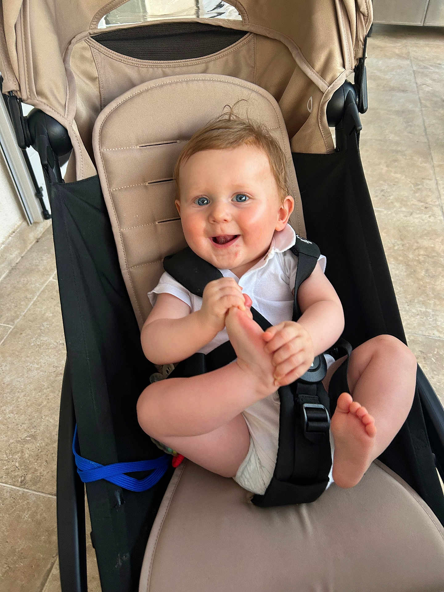 Charlie a rejoint le concours — aidez-le/la à gagner de superbes lots ! baby, child, stroller, seatbelt, foot, hands, smiling, happy, indoor, floor, tile, clothing, white_shirt, hair, face, blue_eyes, infant, cute, person, sitting