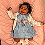 baby, child, smiling, blue_dress, white_cardigan, pink_blanket, stars, happy, infant, cute, lying_down, socks, indoor, portrait, face, dark_hair, adorable, playful, young_child, cheerful