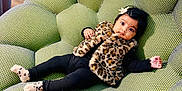 Anjena participe au concours pour gagner de l'argent avec cette photo : baby, child, infant, furniture, chair, green, plush, texture, leopard_print, vest, socks, black_clothing, bow, cute, indoor, floor, wooden_floor, person, portrait, relaxing