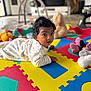 baby, indoor, colorful, foam_mat, plush_toys, curious, lying_down, child, soft_toys, floor, play_area, infant, cute, person, young_child, bright_colors, home, cozy, portrait, attention