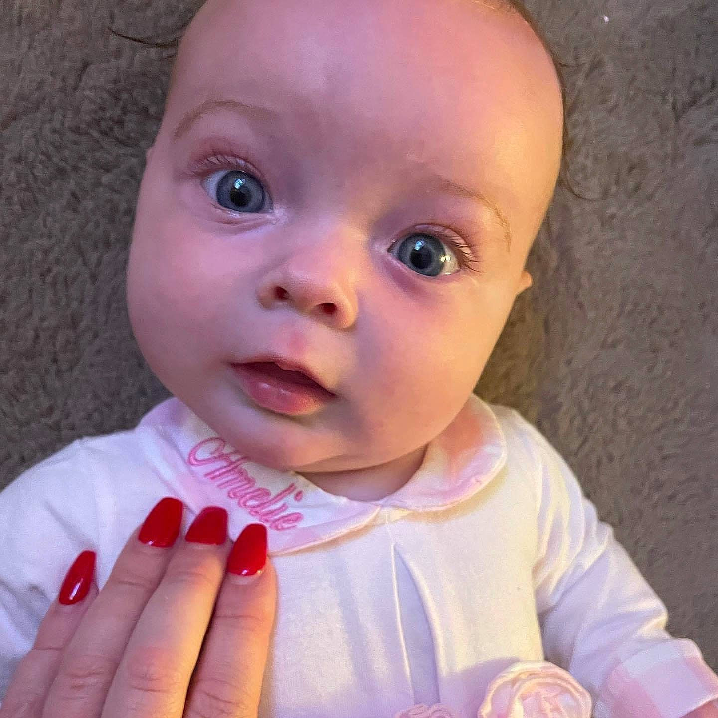 Amelie is registered to the contest to win money with this photo: baby, baby_toddler_clothing, cheek, ear, eyebrow, eyelash, face, finger, gesture, happy, iris, lip, mouth, nose, organ, person, pink, skin, sleeve, smile