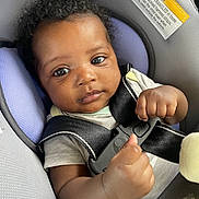 Kahlani joined the competition — help win amazing prizes! baby, car_seat, child, infant, seatbelt, straps, face, curly_hair, clothing, looking, young_child, safety, car_interior, person, portrait, cute, hands, expression, seat, indoor