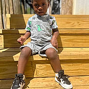 Messiah joined the competition — help win amazing prizes! toddler, child, boy, overalls, dinosaur, shirt, sneakers, shoes, wooden_steps, outdoor, daylight, sunlight, casual_clothing, portrait, expression, person, young_child, fashion, summer, seated