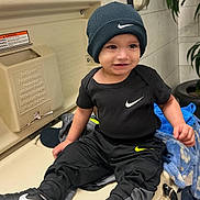 Josue joined the competition — help win amazing prizes! beanie, black_clothing, blanket, casual_wear, changing_table, child, cute, footwear, hat, indoor, nike, person, plant, portrait, public_restroom, smiling, sneakers, tile_wall, toddler, young_child